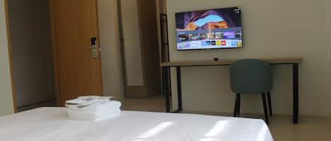 Una habitación de hotel con cama, escritorio, televisor y una silla.