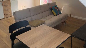 Een moderne woonkamer met een bank, een eettafel en een kitchenette.