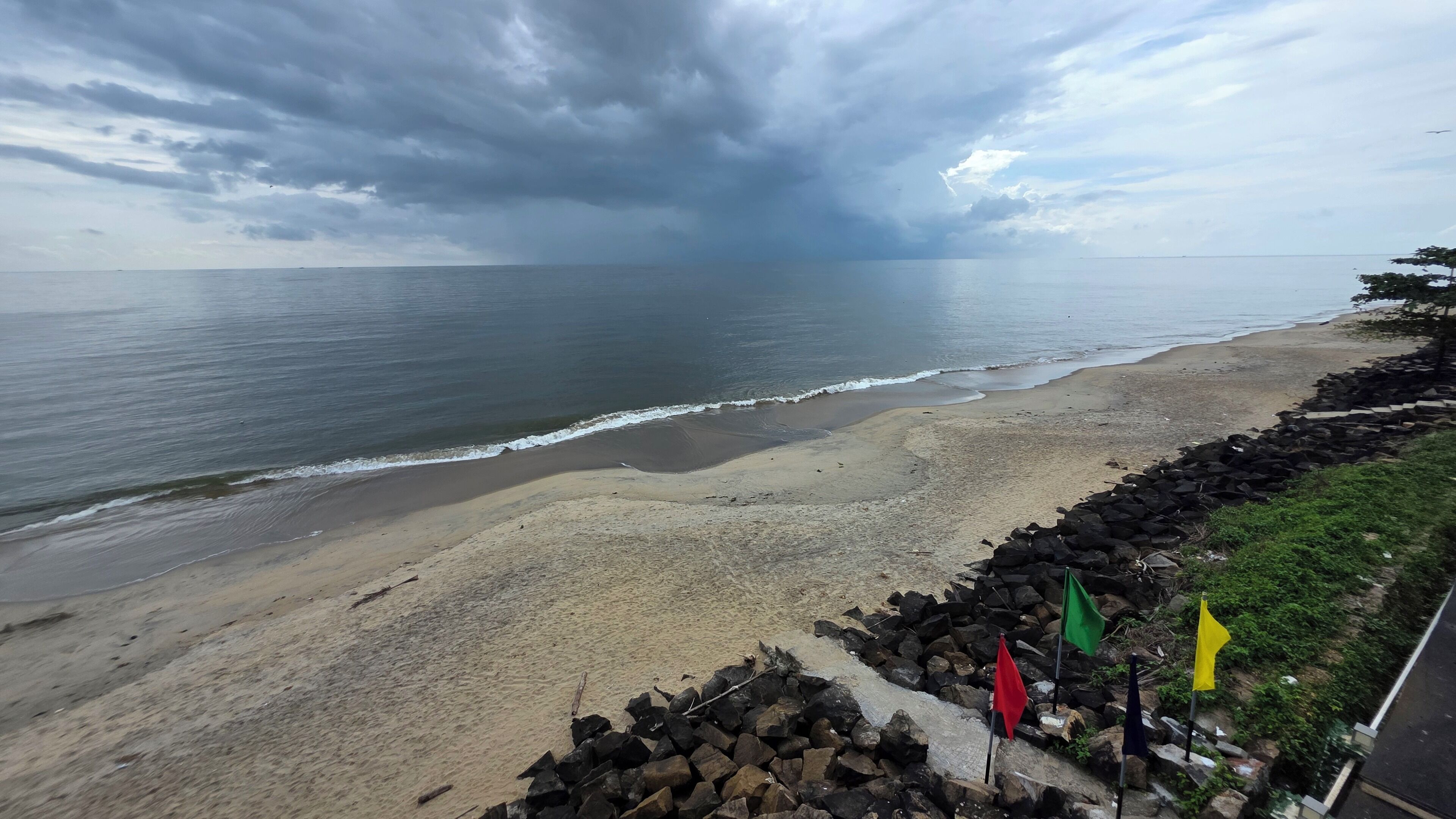 A beach with a rocky shoreline, waves, and a cloudy sky.