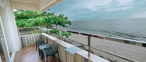 Un balcone con vista sul mare, un tavolo, sedie e una ringhiera.