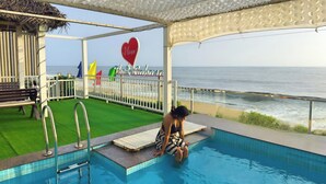 A pool area with a view of the ocean, a bench, and a sign that says "I love The Bahamas". - The Cabana (Kochi)