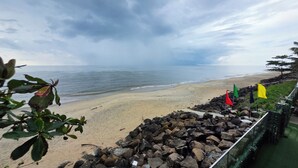A beach with a rocky barrier and flags. - The Cabana (Kochi)