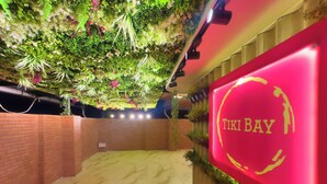 A hotel entrance with a red wall displaying the name 'TIKI BAY'. - The Cabana (Kochi)