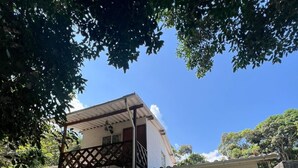 A two-story building with a balcony, a covered porch, and a small garden area. - Betania Cabins (Santa Marta)