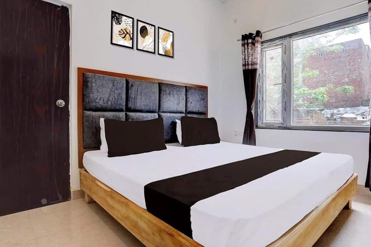 A bedroom with a bed, a window, and three framed pictures on the wall.