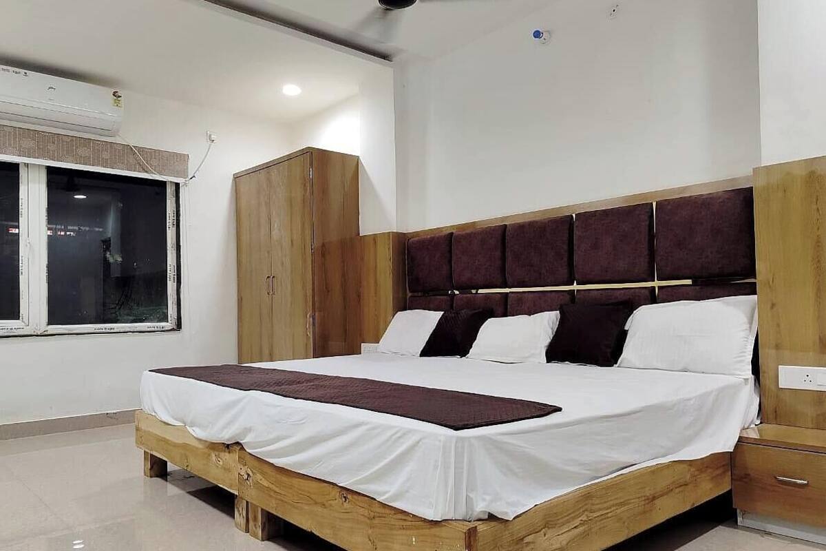 A bedroom with a wooden bed frame, a large window, and a wardrobe.