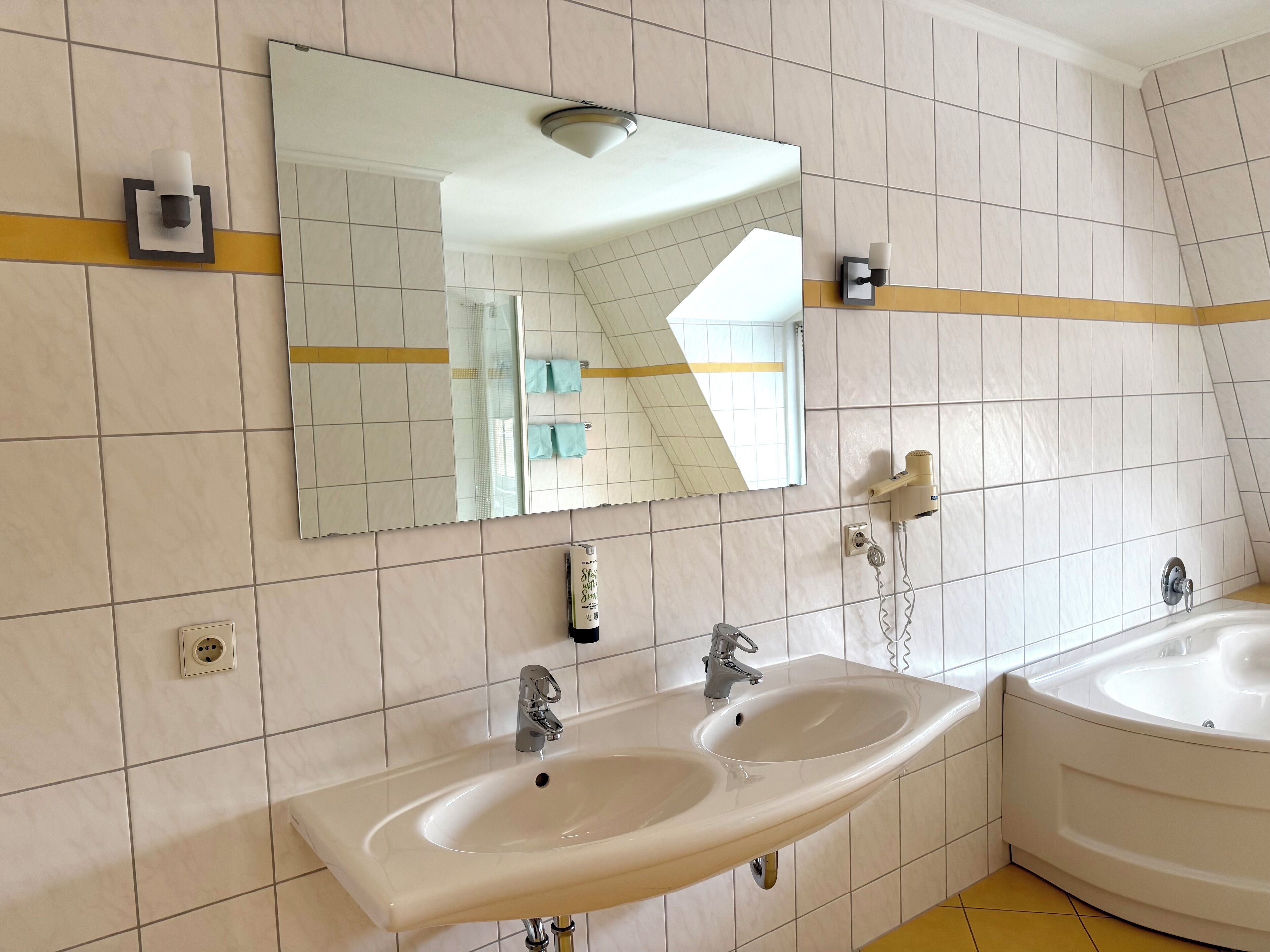 A bathroom with two sinks, a mirror, and a shower.