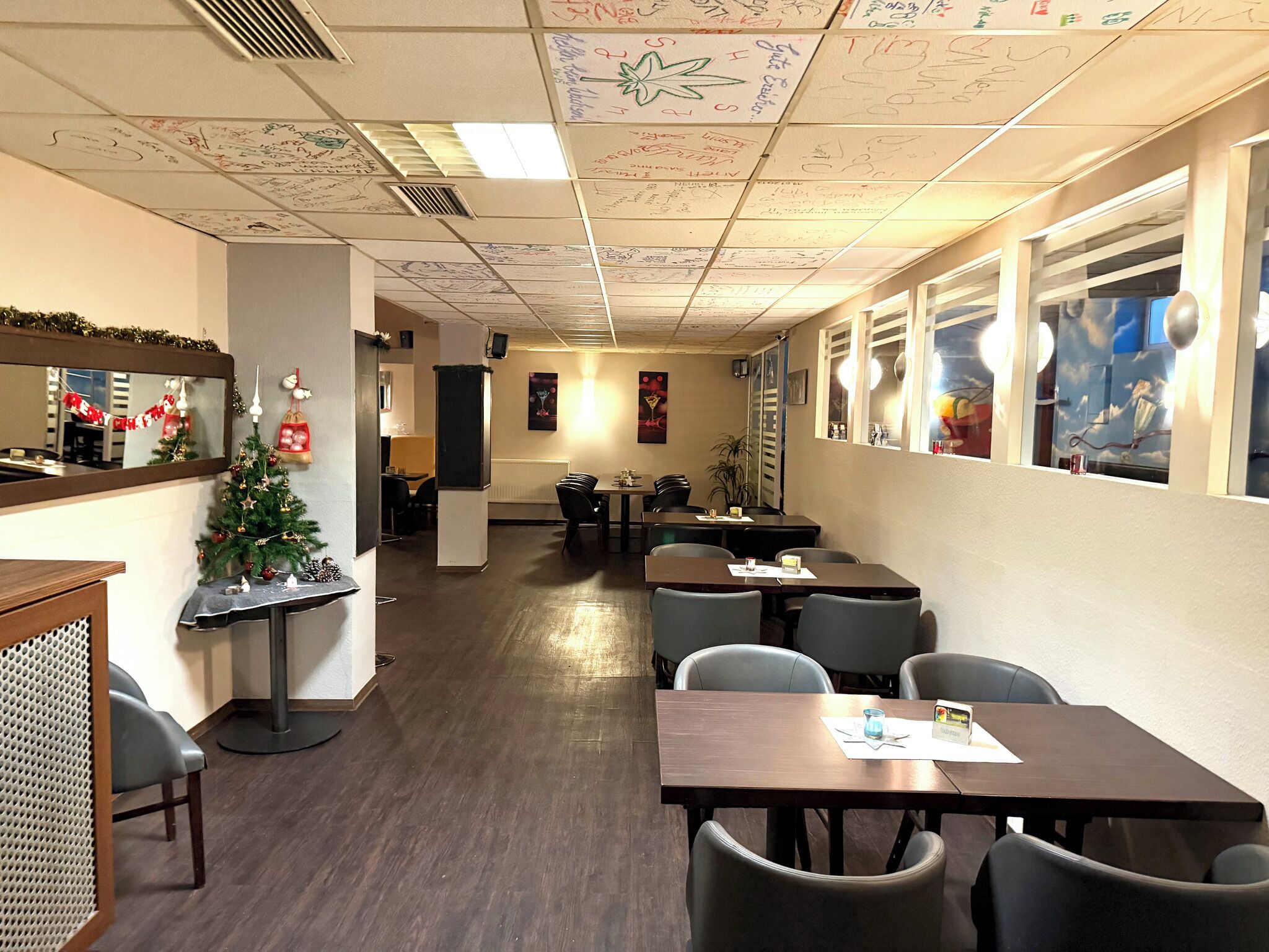 Un restaurante con un árbol de Navidad, mesas, sillas y una pared llena de mensajes escritos a mano.