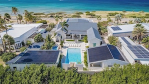 A resort with multiple buildings, a swimming pool, and solar panels. - Oceanfront 10BR Lux Villa • Pool • Full Ocean View (Noord)