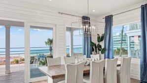 A dining area with a table and chairs, a view of the ocean, and a balcony with a railing. - LUX Family Teddy's Heaven - Beachfront - 6 Seater LSV - Pool-Hottub (Panama City Beach)
