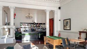 Een bar met een pooltafel en stoelen, een kroonluchter en een bar voorzien van flessen.