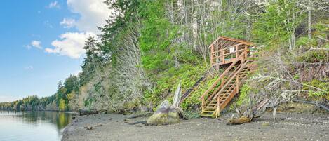 A wooden staircase leading up a rocky shore, surrounded by dense trees and a calm lake.