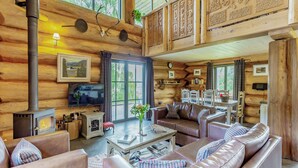A log cabin interior with a fireplace, leather sofas, a dining area, and wooden walls. - 3 bedroom accommodation in Beauly, near Drumnadrochit (Beauly, near Drumnadrochit)