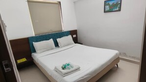 Een hotelkamer met een bed, een raam en een schilderij aan de muur.