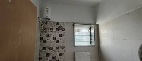 A bathroom with a tiled wall, a window, and a white radiator.