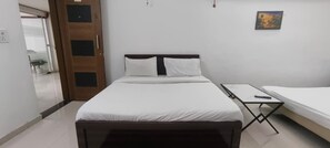 Un dormitorio con una cama, una mesita de noche y una puerta.