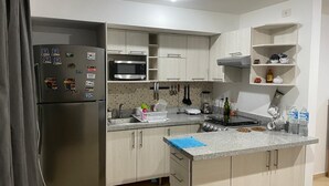 Une cuisine moderne équipée d’un réfrigérateur, d’un four à micro-ondes, d’un évier et d’un plan de travail en granit.