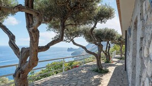 Un sentier pavé de pierres, bordé d’arbres et doté d’une rambarde, d’où l’on peut admirer la vue sur la côte.