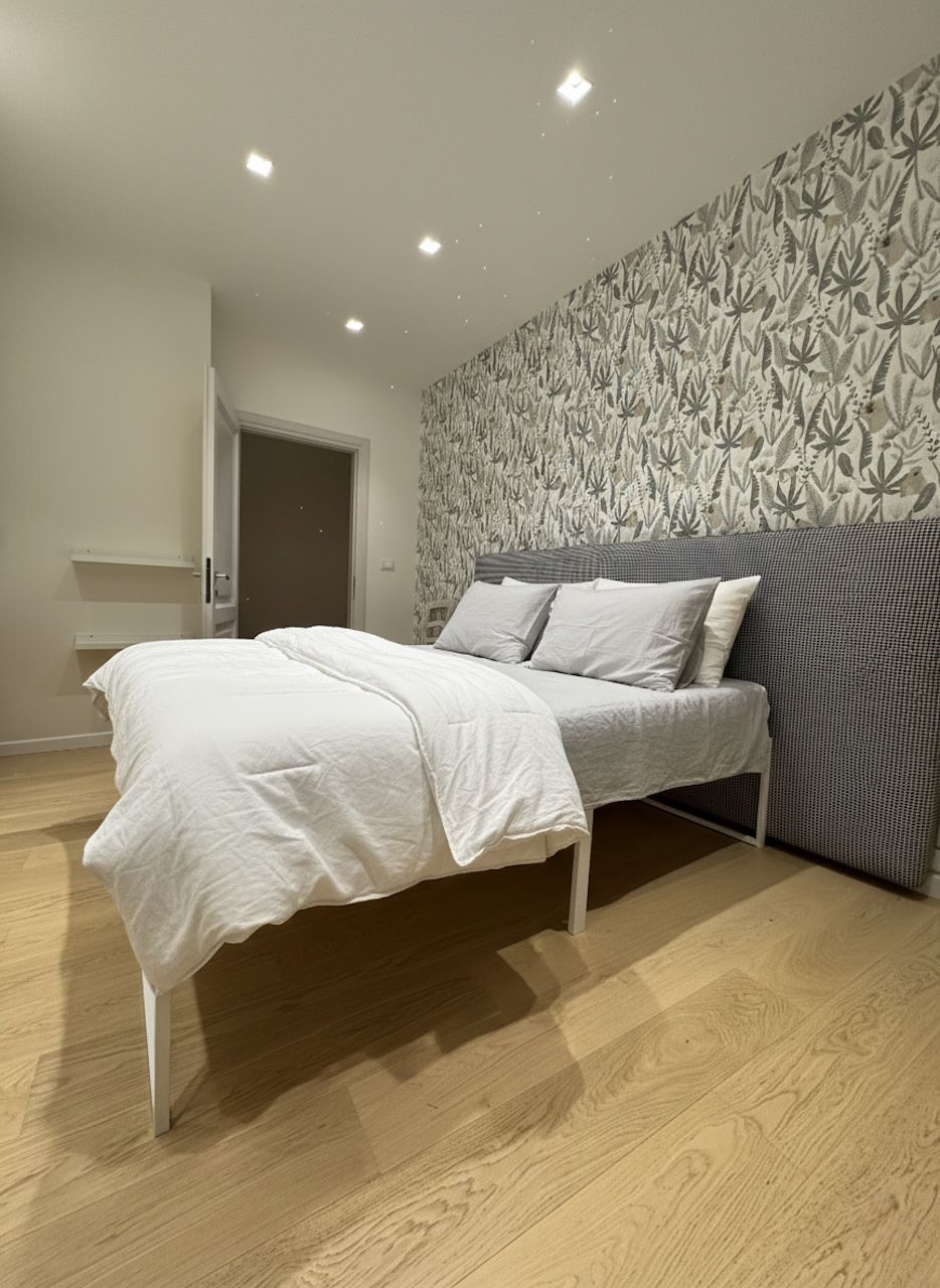 A bedroom with a bed, a patterned wall, and a door.
