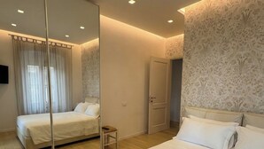 A modern bedroom with a large bed, a mirror, and a door. - Respiro - Lux & Charm in Assisi (Assisi)