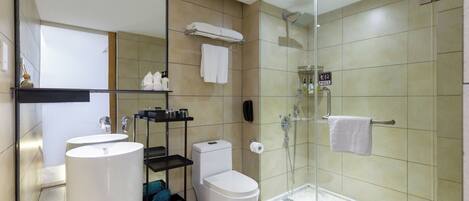 A modern bathroom with a glass-enclosed shower, two sinks, a toilet, and a towel rack.