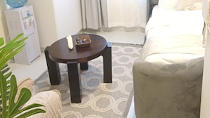 Una habitación de hotel con una cama, un sofá, una mesita, un dispensador de agua y una planta.
