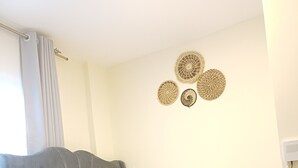 Un dormitorio moderno con un sofá cama gris, una mesita redonda con una cesta y arte decorativo en la pared.