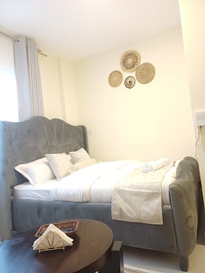 Ein modernes Schlafzimmer mit einer grauen Schlafcouch, einem kleinen runden Tisch mit einem Korb und Wanddekoration.