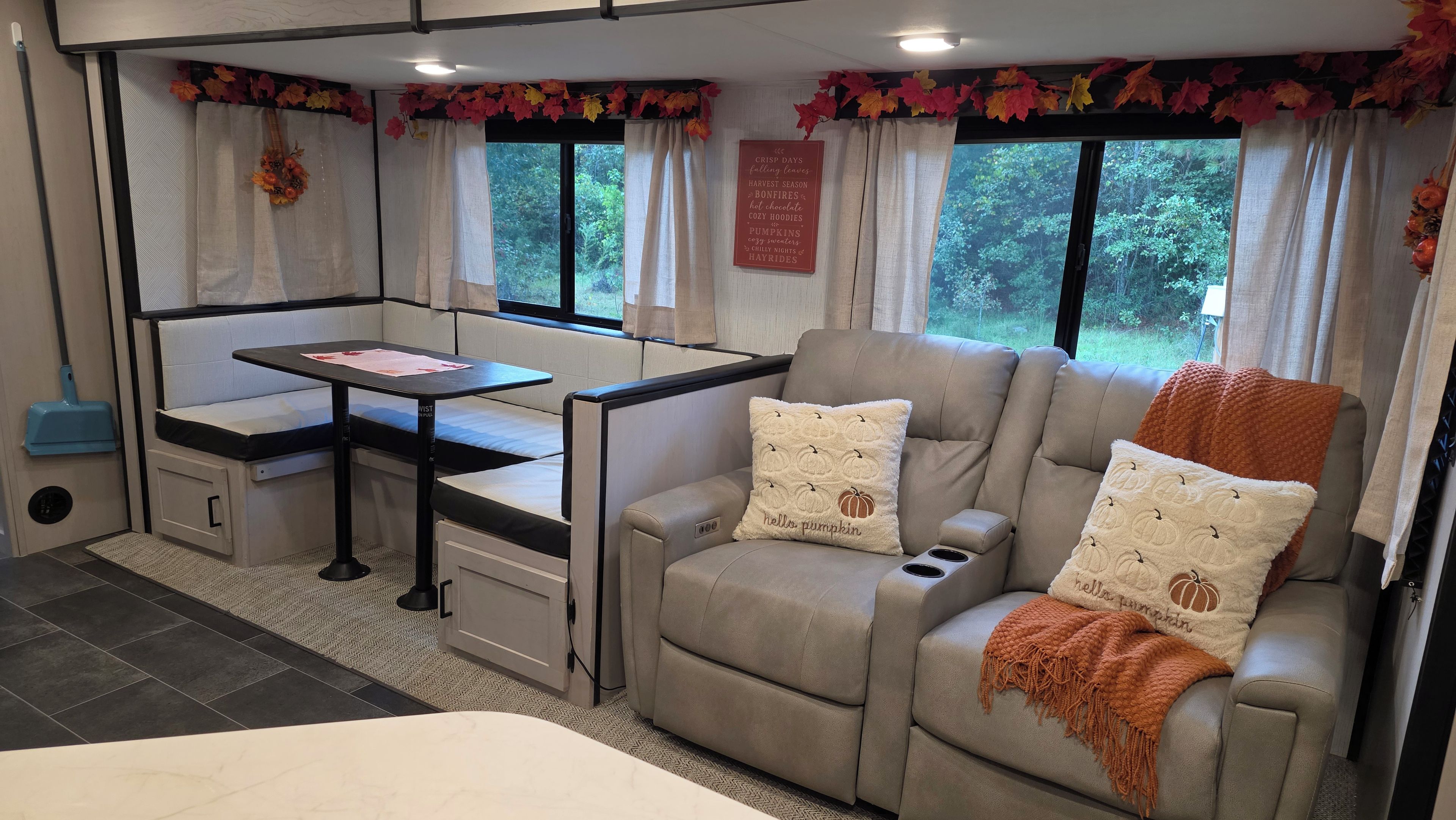 A cozy RV interior with a seating area, a table, and a window with curtains.