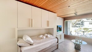 Un dormitorio moderno con cama empotrada, techo de madera y vistas al exterior.