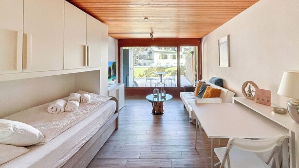 Habitación compacta con cama, una mesita y un sofá. Una ventana ofrece vistas al exterior.