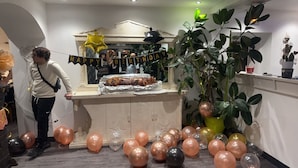 Una habitación con un mostrador que muestra un plato asado, globos y un cartel que dice 'FELIZ CUMPLEAÑOS'.
