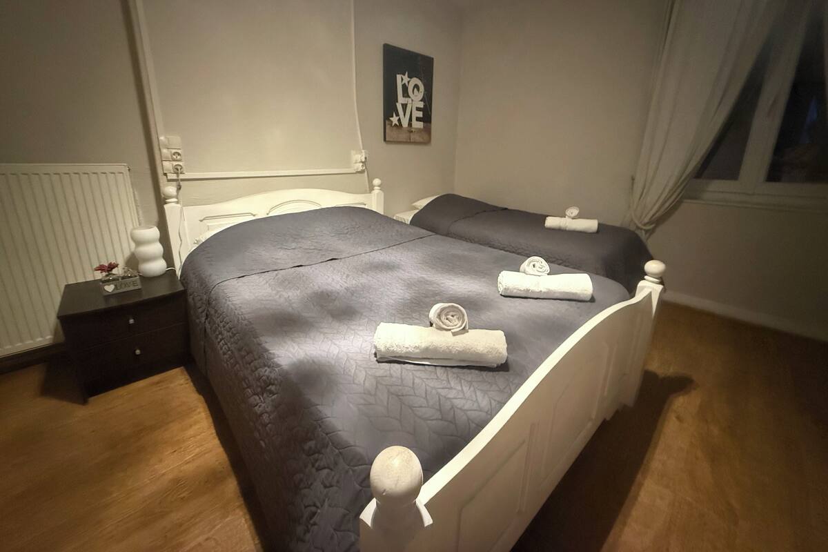 Un lit double avec une couette bleu foncé, deux oreillers et des serviettes enroulées posées sur le lit.