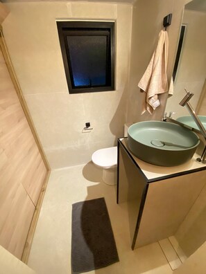 A modern bathroom with a large sink, a toilet, and a small window above the toilet. - Pitanga House - Ponta do Papagaio Beach (Palhoça)
