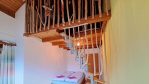 Une pièce avec un escalier en bois, un lit avec une literie rose et un plancher en bois.