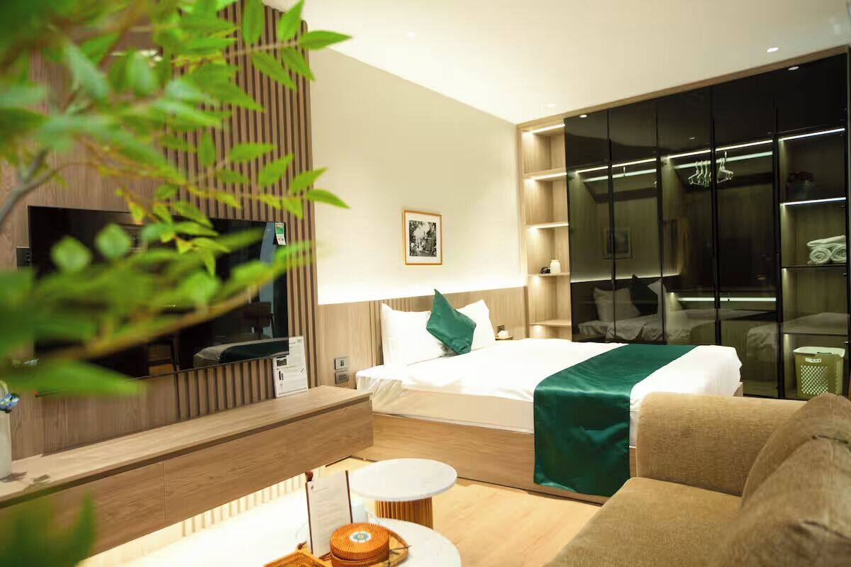 A modern hotel room with a bed, a sofa, a TV, and a wardrobe.