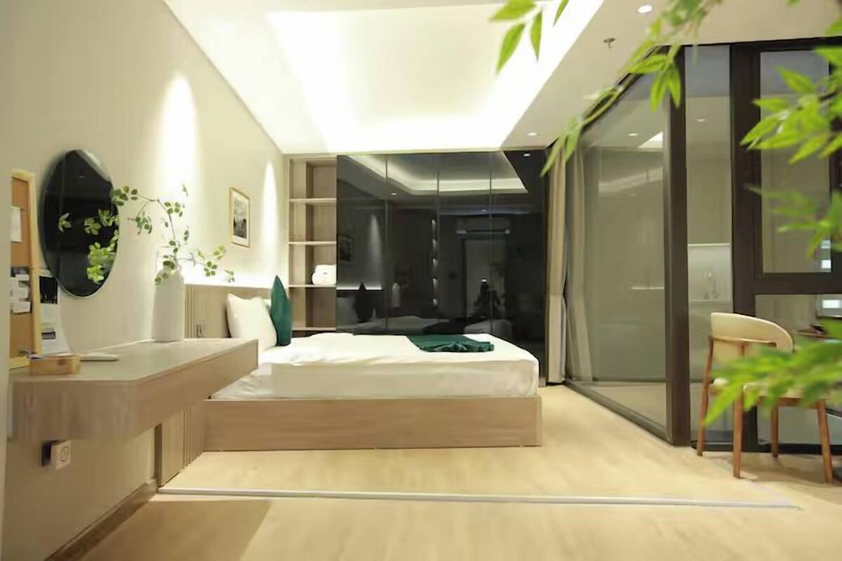 A modern bedroom with a skylight, a bed, a desk, and a chair.