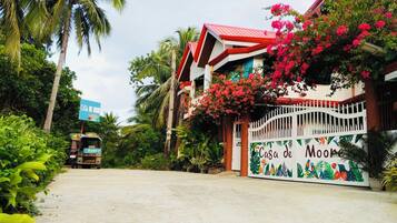 A tropical resort with a colorful entrance gate, lush greenery, and a clear sky.