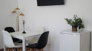 A small, modern room with a white table, two black chairs, a white cabinet, a floor lamp, and a potted plant. - Group Stay Comfortable Multi Apart (Vienna)