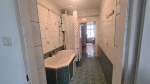 Ein schmales Badezimmer mit Badewanne, Dusche und Toilette.