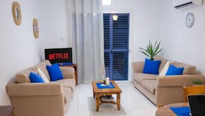 Een woonkamer met twee banken, een salontafel, een televisie en een laptop.