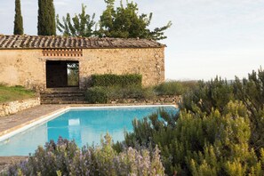 A stone building with a pool, surrounded by greenery and trees. - Podere Sangiovese, pool and view in Chianti region (Castellina In Chianti)