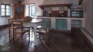 Een landelijke keuken met houten balken, een eettafel met stoelen en een kleine oven.