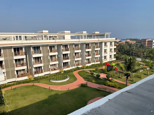 A multi-story hotel with balconies, a central courtyard, and a playground. - Rohm Staycations (Gopalpur)