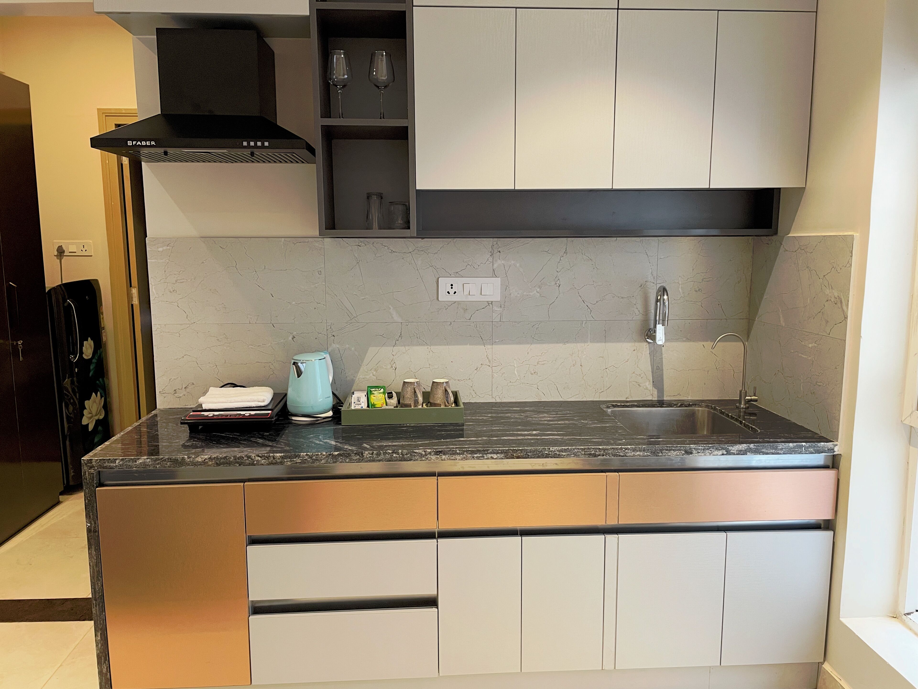 A modern kitchen with a black countertop, stainless steel sink, and white cabinets.