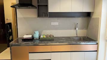 A modern kitchen with a black countertop, stainless steel sink, and white cabinets.