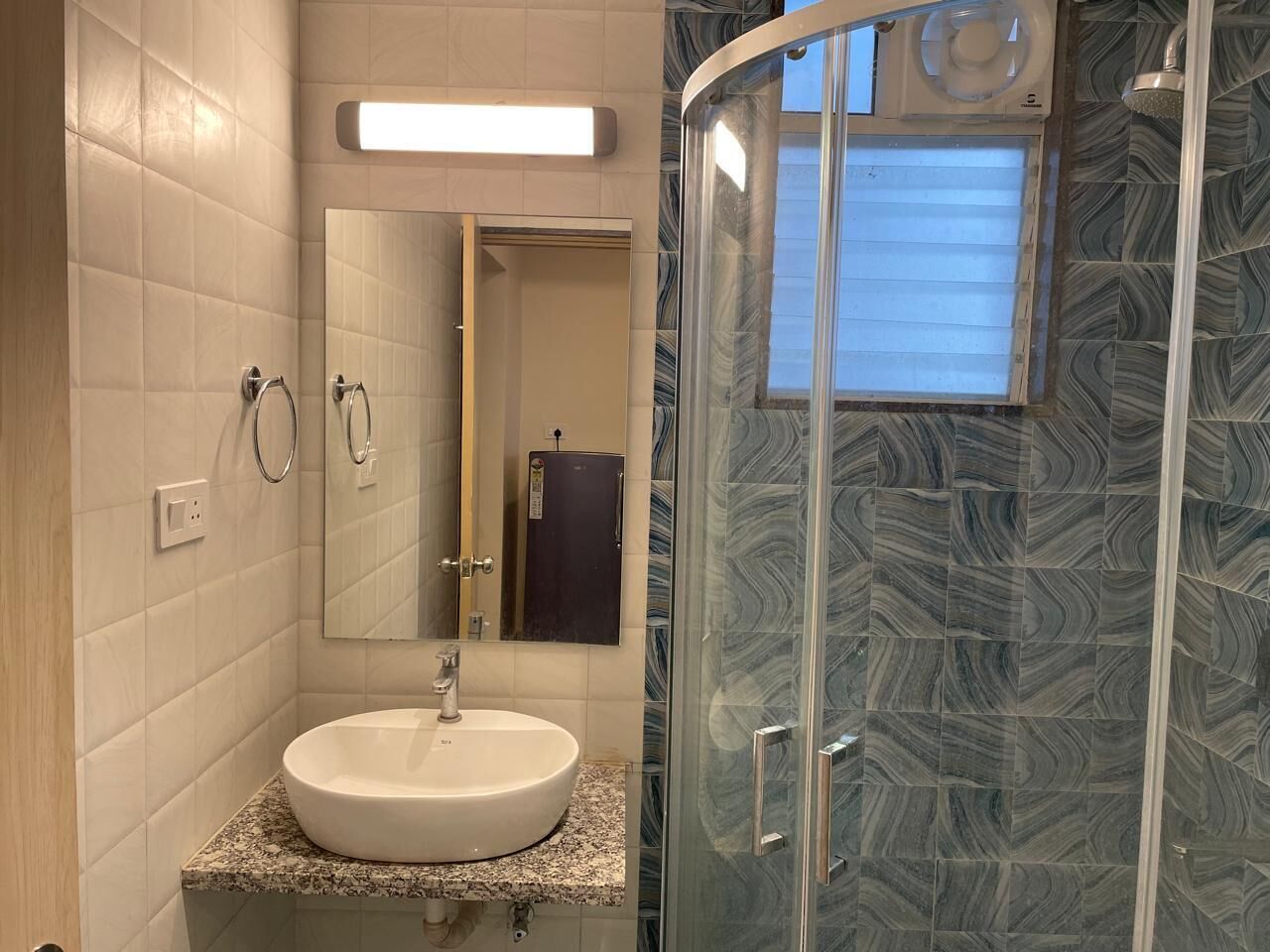 Un baño con un lavabo blanco, un espejo y una ducha con puerta de cristal.