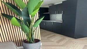Et moderne køkken med mørke skabe og en potteplante.