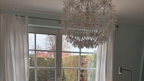 Ett modernt vardagsrum med en soffa, sittpallar, en fåtölj och ett stort fönster med gardiner.