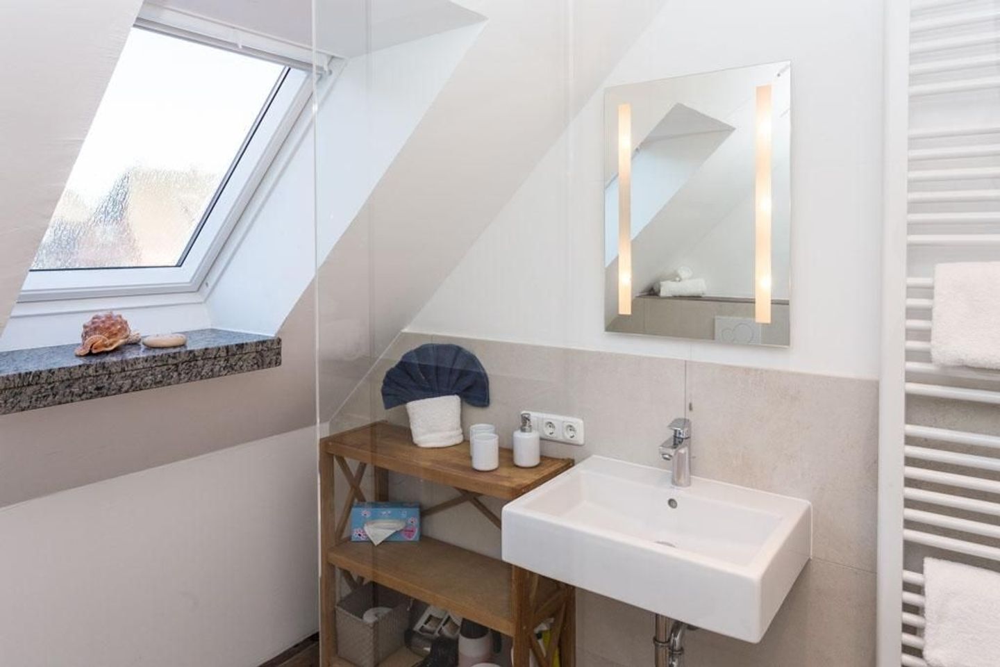 A modern bathroom with a skylight, a large mirror, and a white sink.